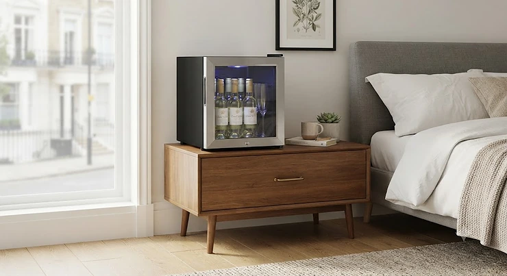 A compact mini wine cooler for bedroom placement sitting neatly on a stylish bedside cabinet in a modern British flat.