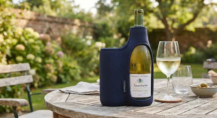 A wine bottle cooler sleeve keeping a bottle of crisp white wine chilled on a garden table